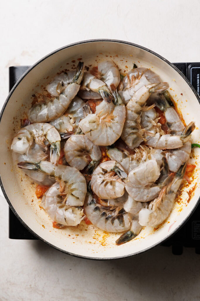adding the prawns to the pan.