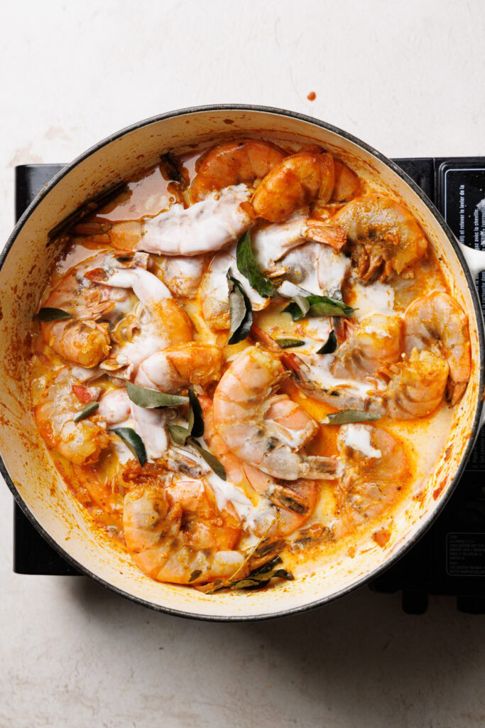 adding coconut milk to the prawn curry.