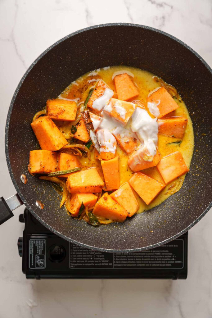 adding coconut milk to the pot.