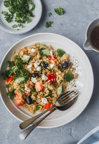 mediterranean quinoa salad in a bowl with dressing on the side