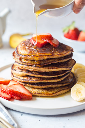 Healthy Banana Oat Pancake stacked on a plate topped with fruits