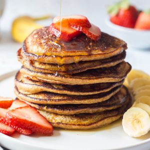 Healthy Banana Oat Pancake stacked on a plate topped with fruits