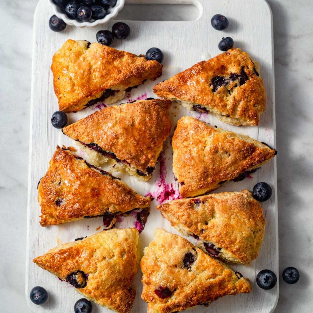 air fryer blueberry scones with blueberries around on a chopping board