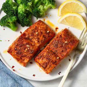air fryer salmon on the plate with broccoli and lemon wedges