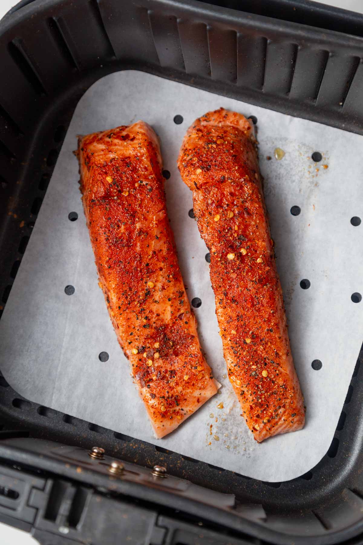placing the seasoned salmon in the air fryer.