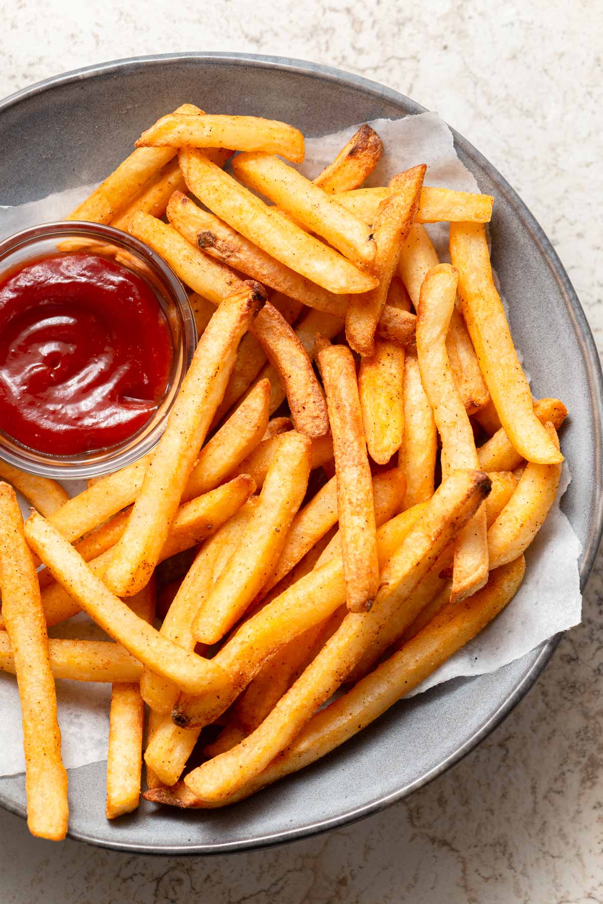 air fried frozen frech fries on a plate with ketchup.