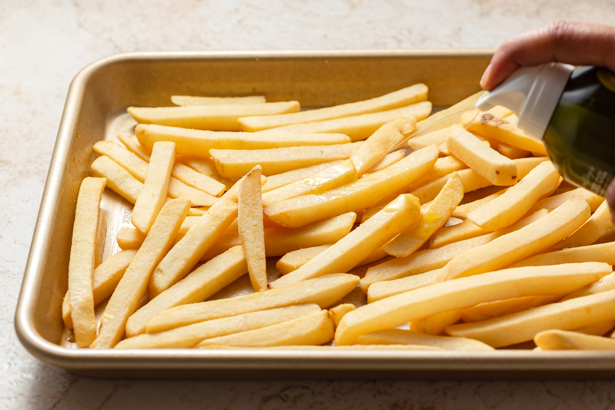 spraying frozen french fries with oil