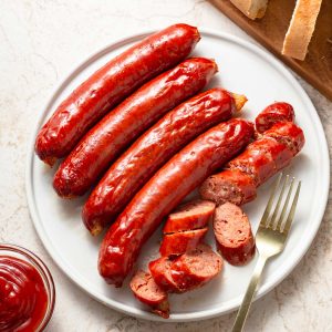 sausages cooked in the air fryer on a plate with one cut up.