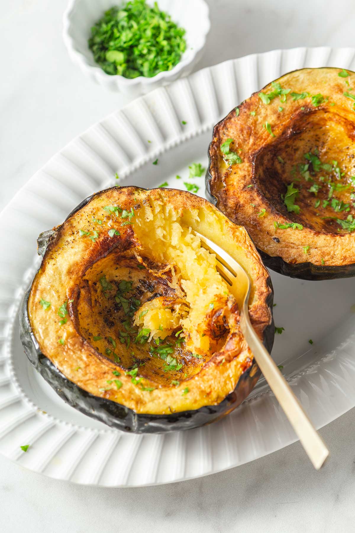 air fryer acorn squash with parsley on a plate with a fork.