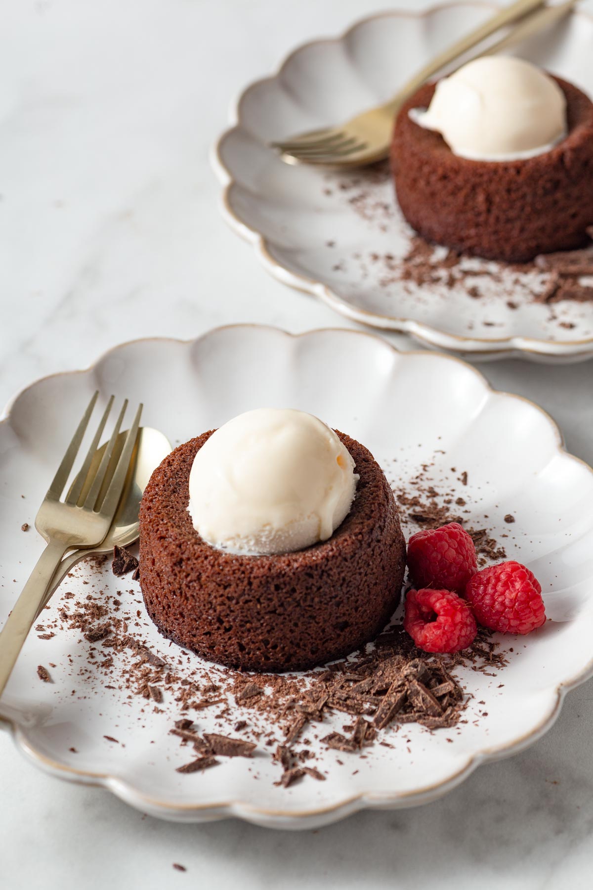 air fryer chocolate lava cake with ice cream on top and raspberries on the side.