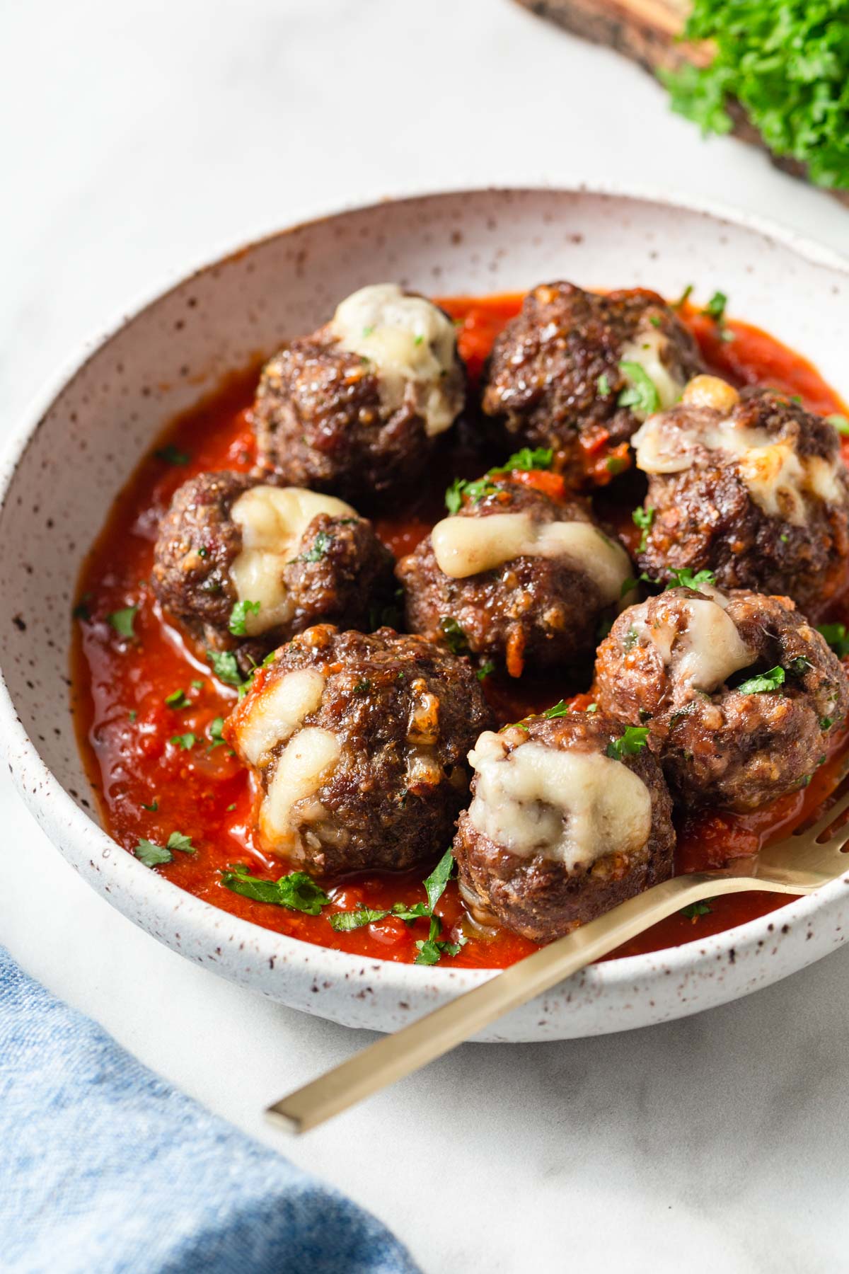 mozzarella stuffed air fryer meatballs with marinara sauce in a bowl with a fork.