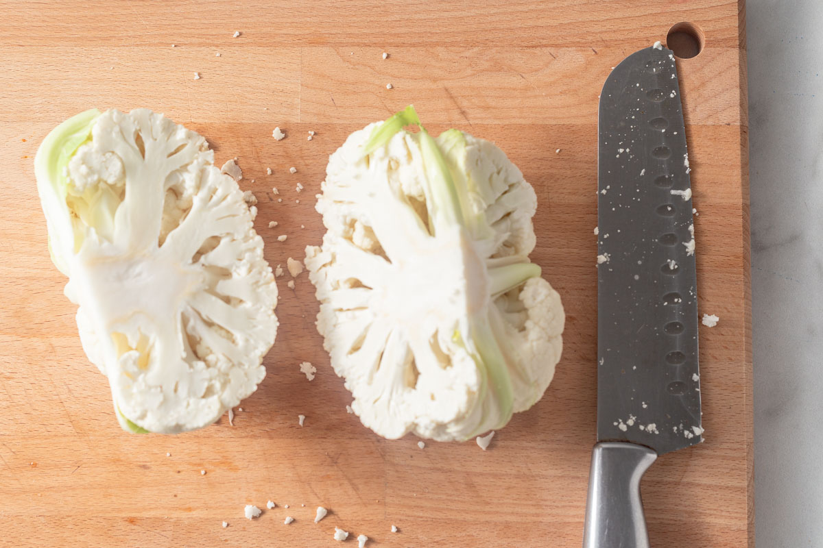 cutting cauliflower into two with a sharp knife.