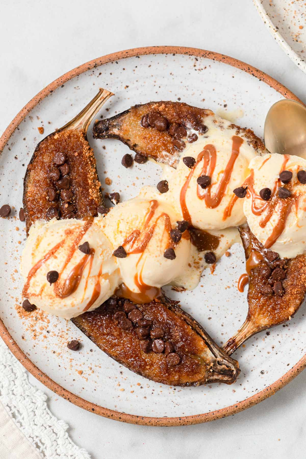 air fryer caramelized bananas on a plate with ice cream and caramel syrup.