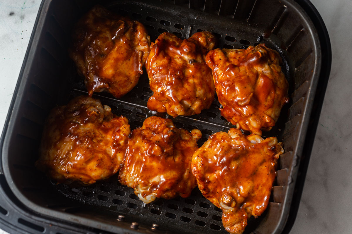 chicken thighs with barbecue sauce in the air fryer basket.