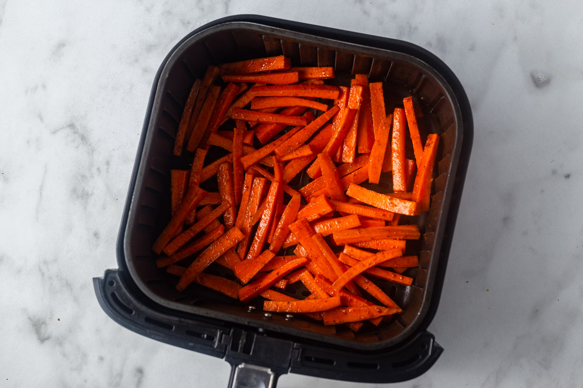 placing carrot fries in the air fryer.