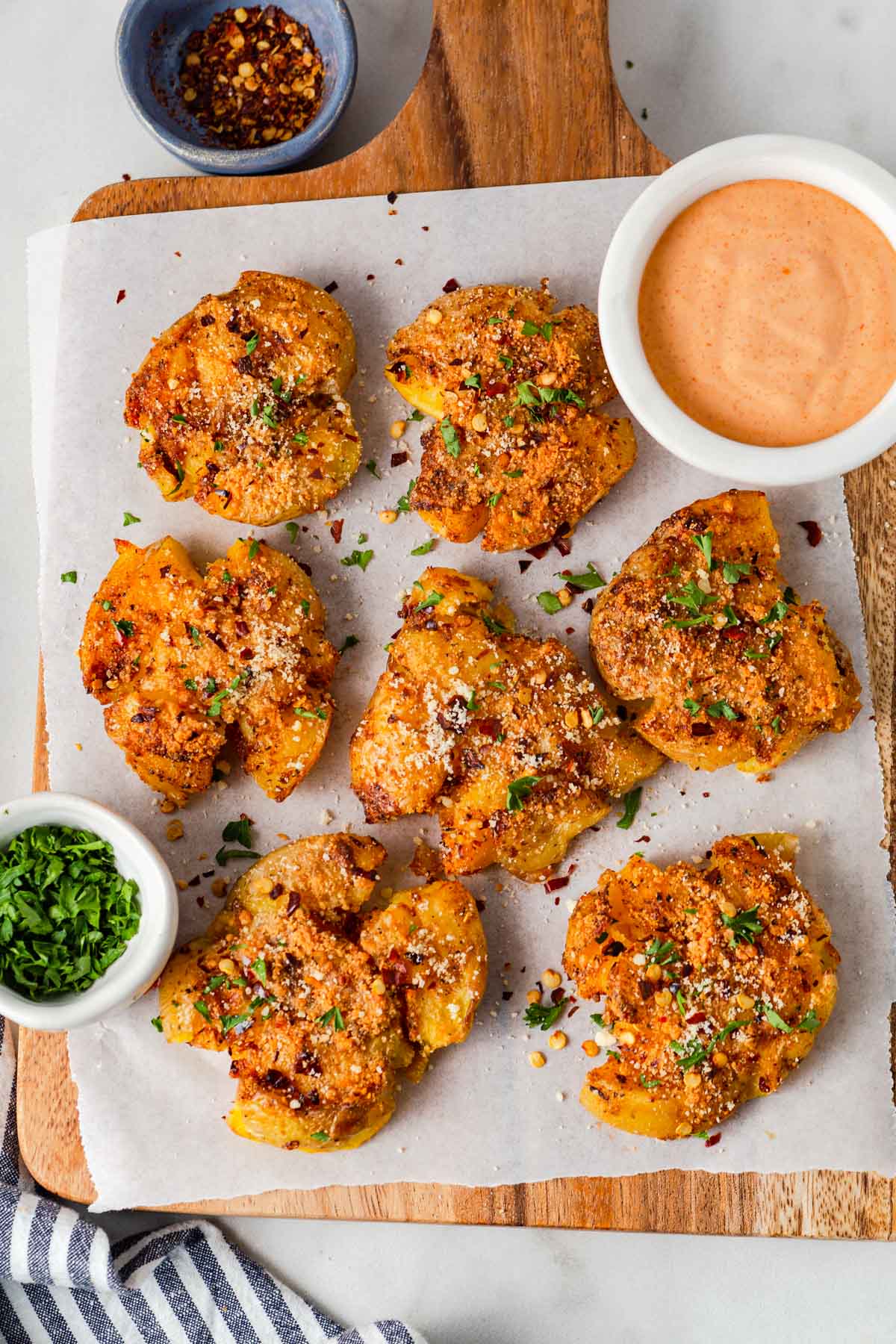air fryer crispy smashed potatoes on a board with dipping sauce.