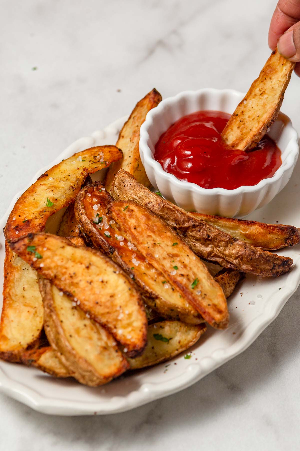 crispy air fryer potato wedges dipped in ketchup.