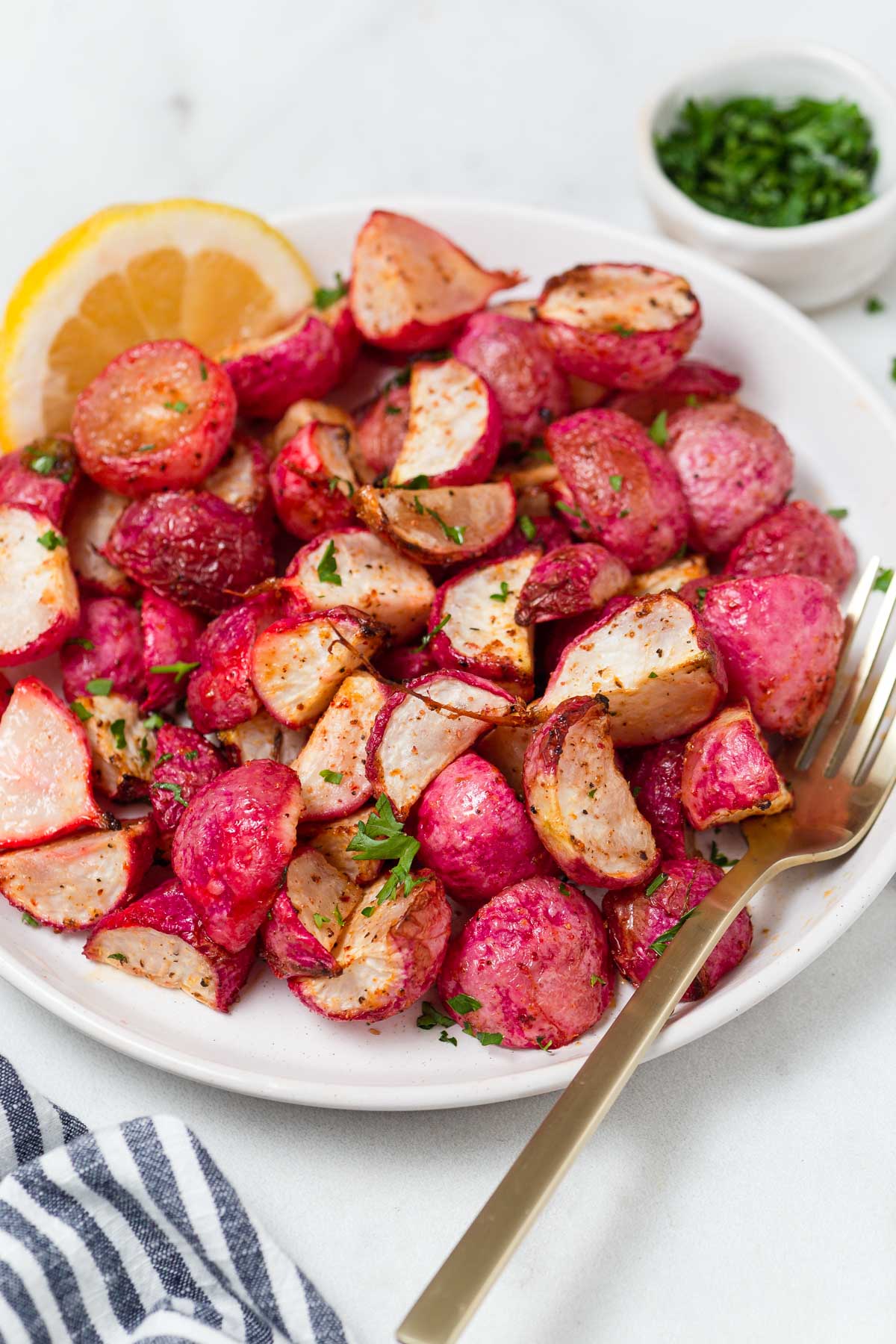 air fryer radishes in a plate with a lemon wedge.