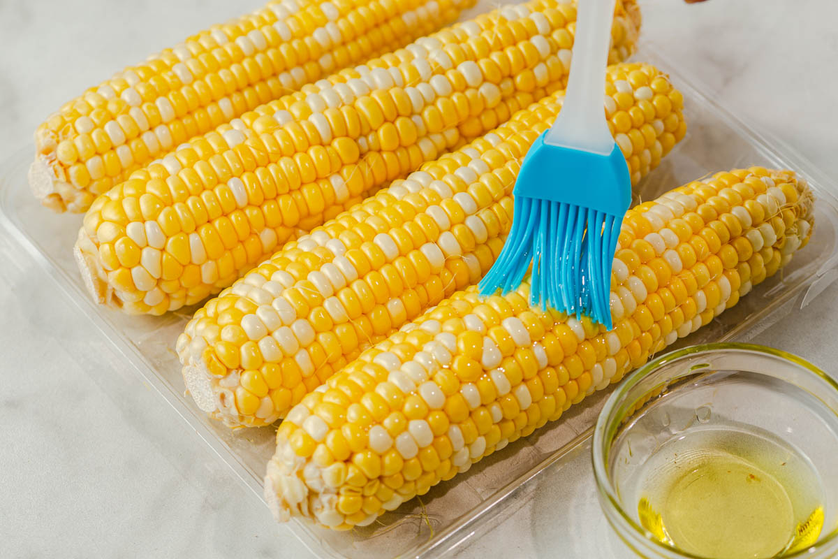 brushing oil on the corn cobs.