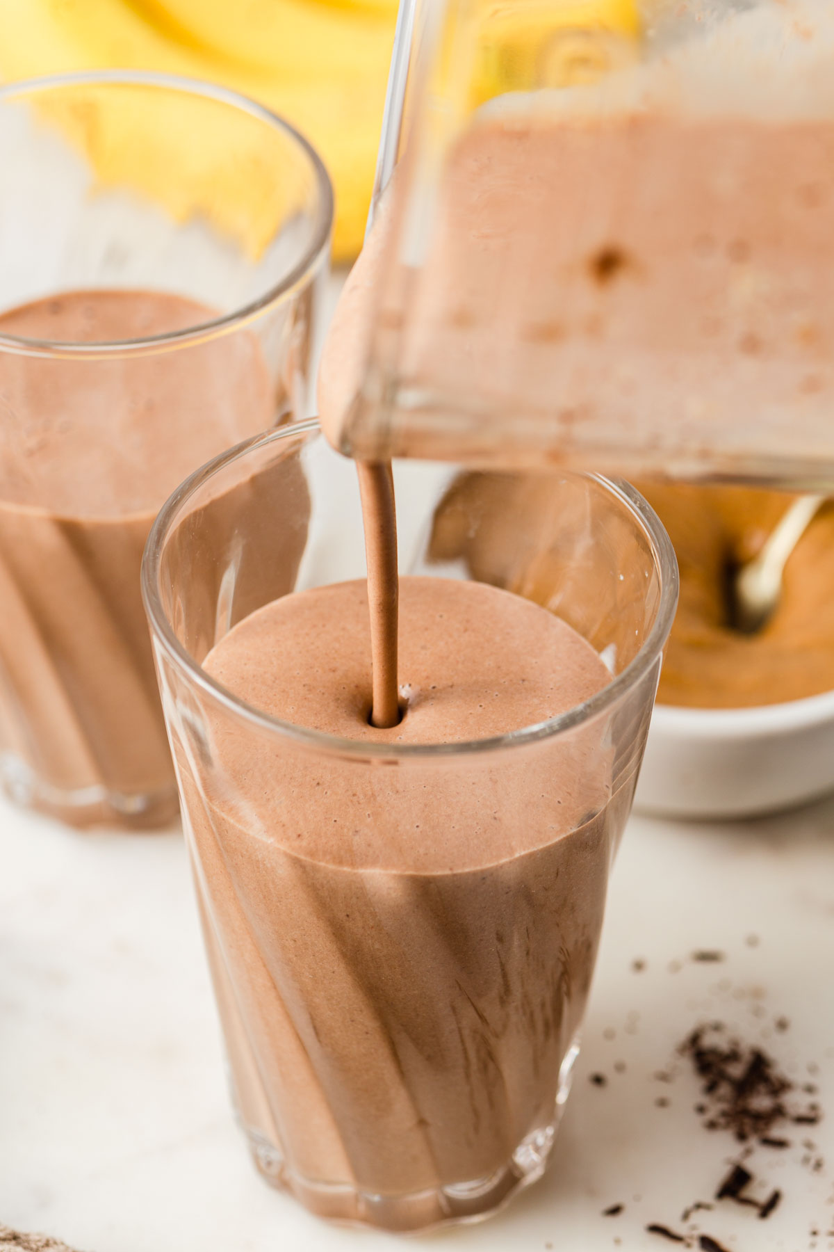 pouring the chocolate peanut butter  banana smoothie to the glass.