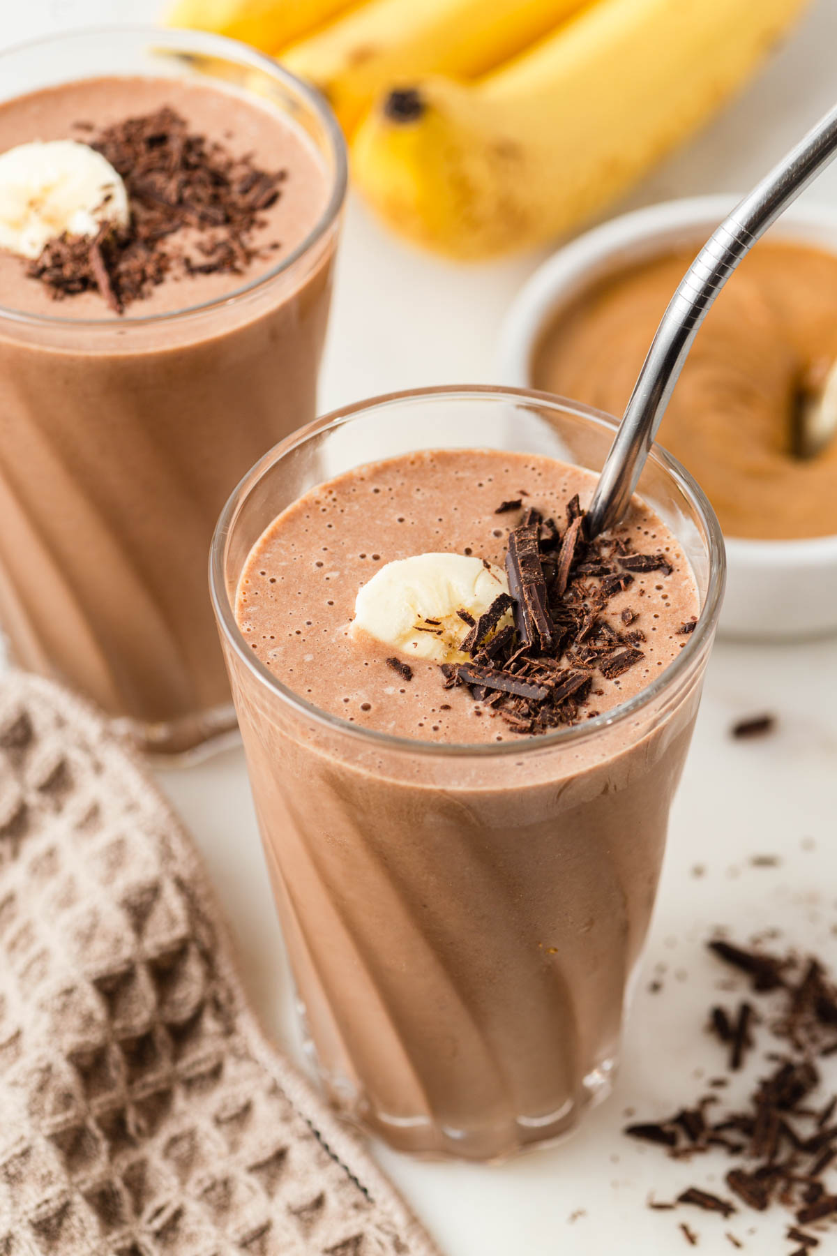 chocolate peanut butter banana smoothie in a glass with banana and grated chocolate.