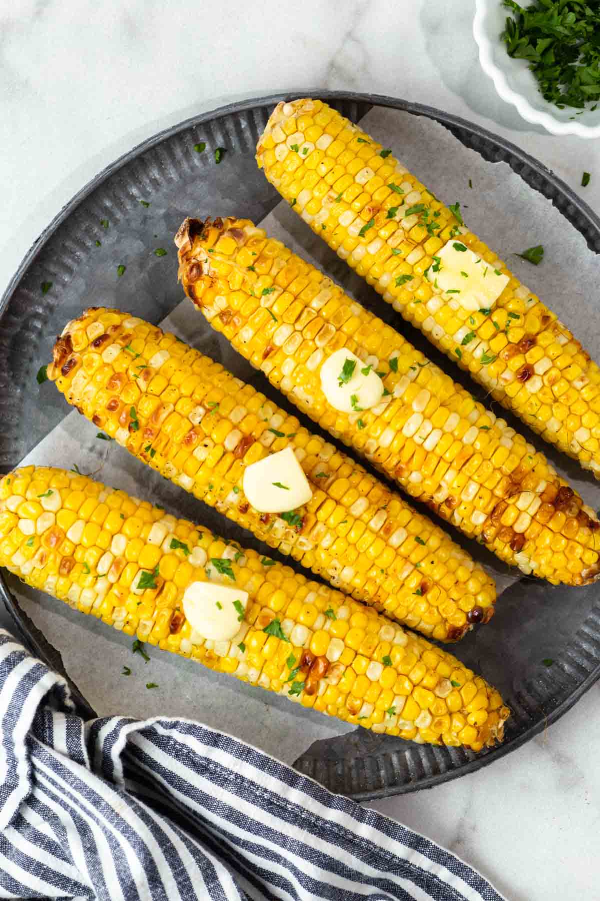 air fryer corn on the cob with butter on a plate.