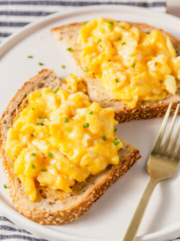 air fryer scrambled eggs on toast with a fork on the side.