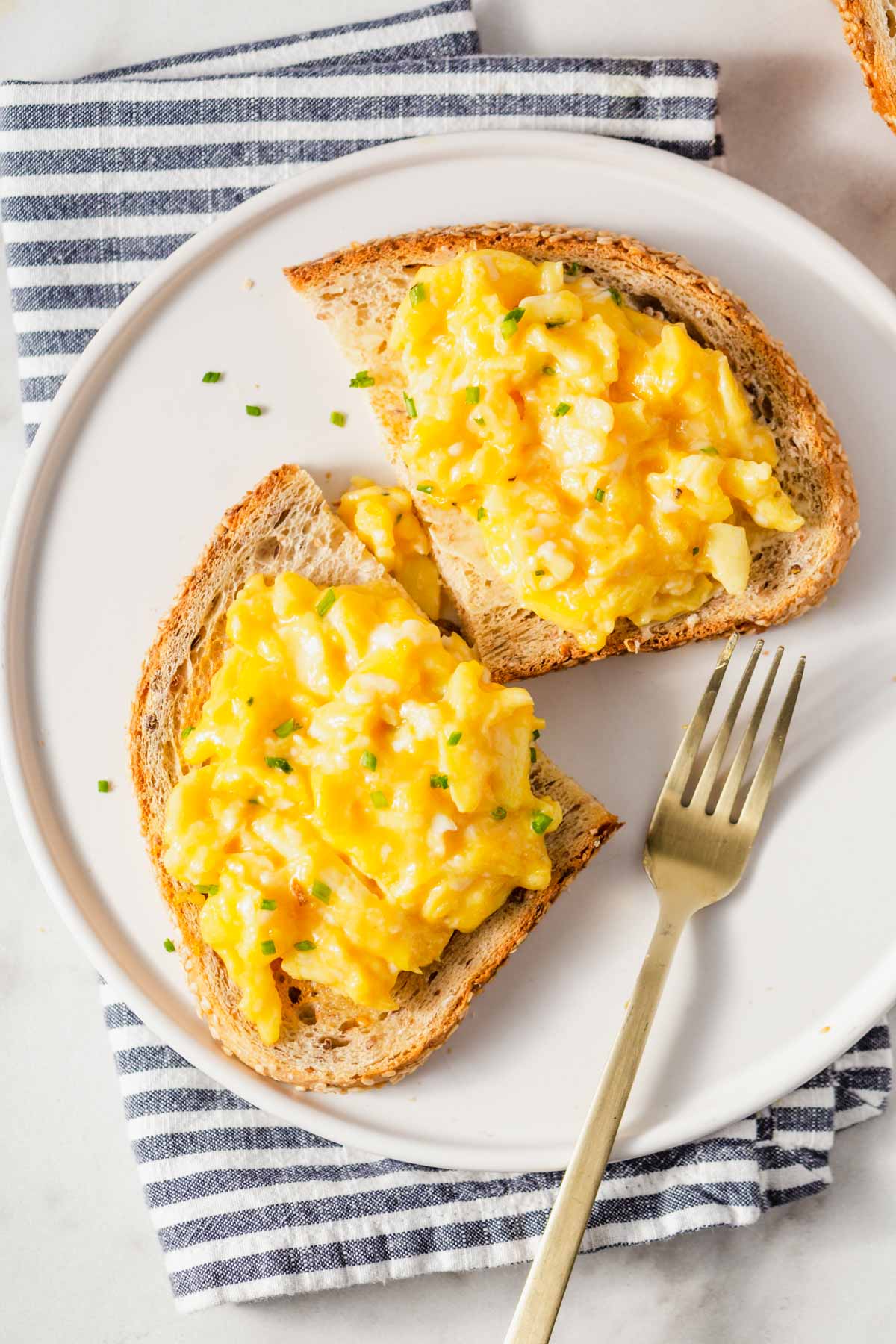 air fryer scrambled eggs on toast with fork on the side.