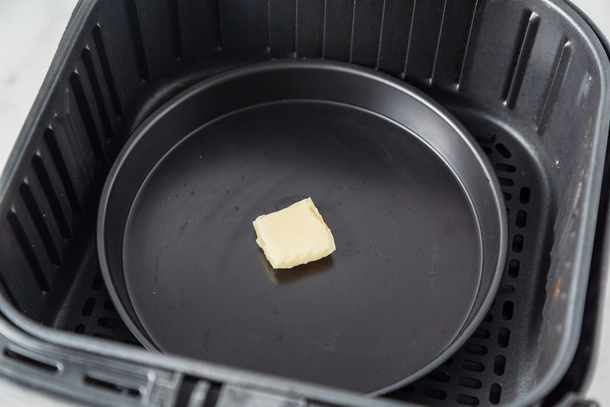 placing butter on a pan inside the air fryer.