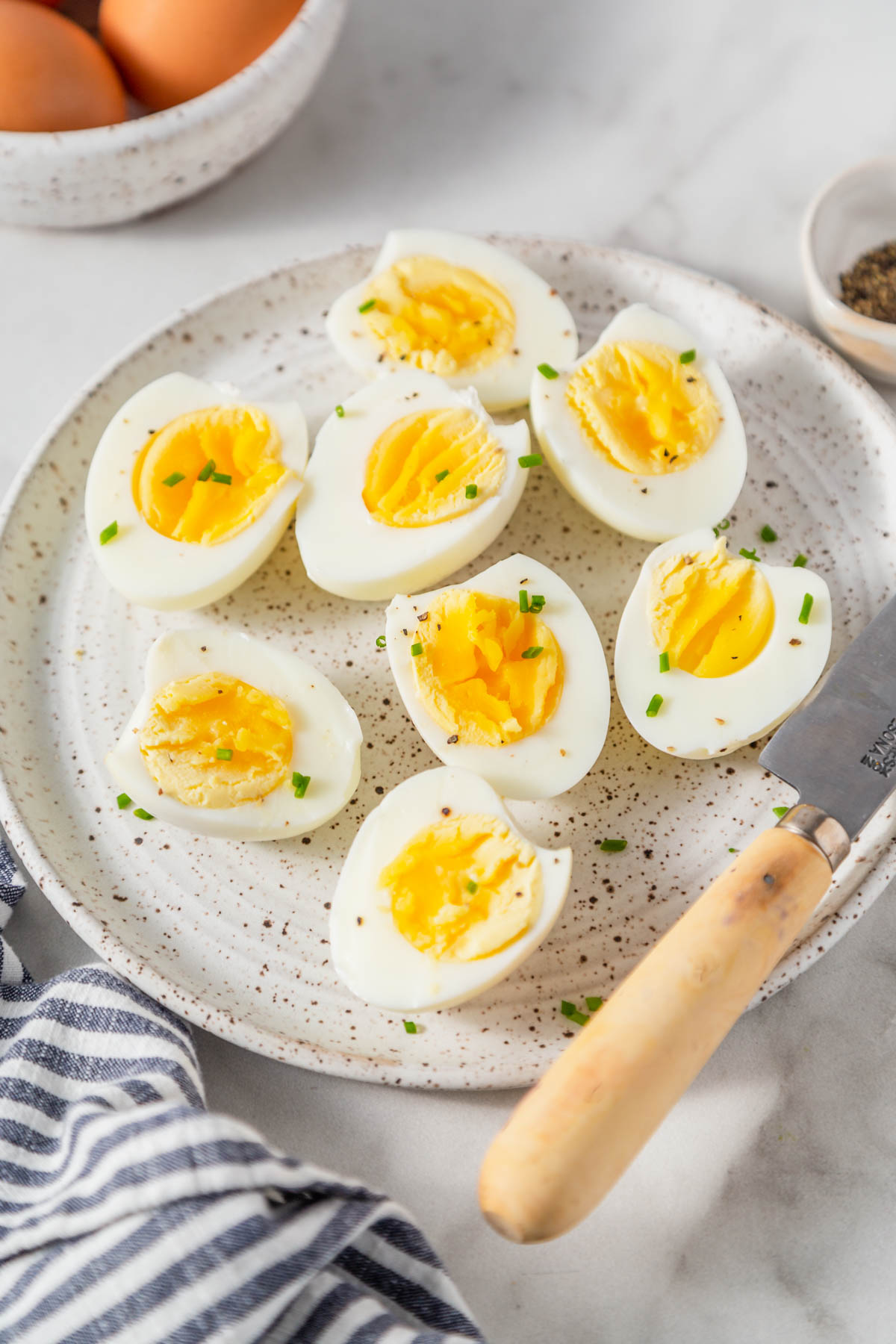 Air fryer hard boiled eggs cut in half on a plate sprinkled with black pepper.