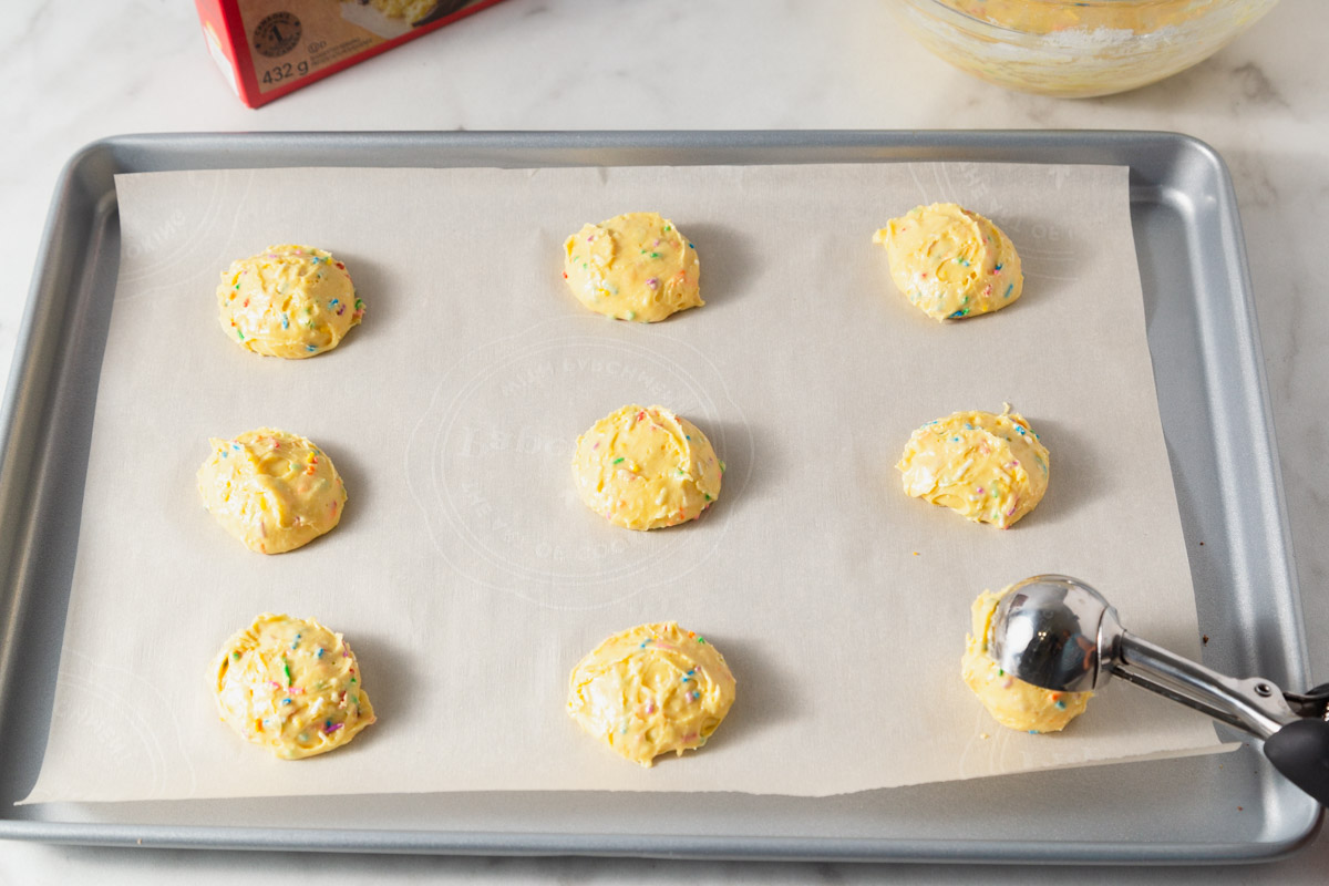 scooping the yellow cake mix cookie dough to the baking sheet.