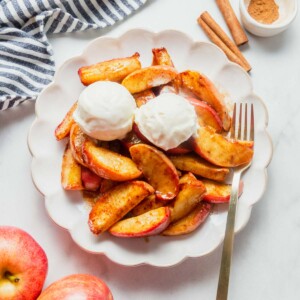 air fryer cinnamon apples on a plate served with ice cream on top.