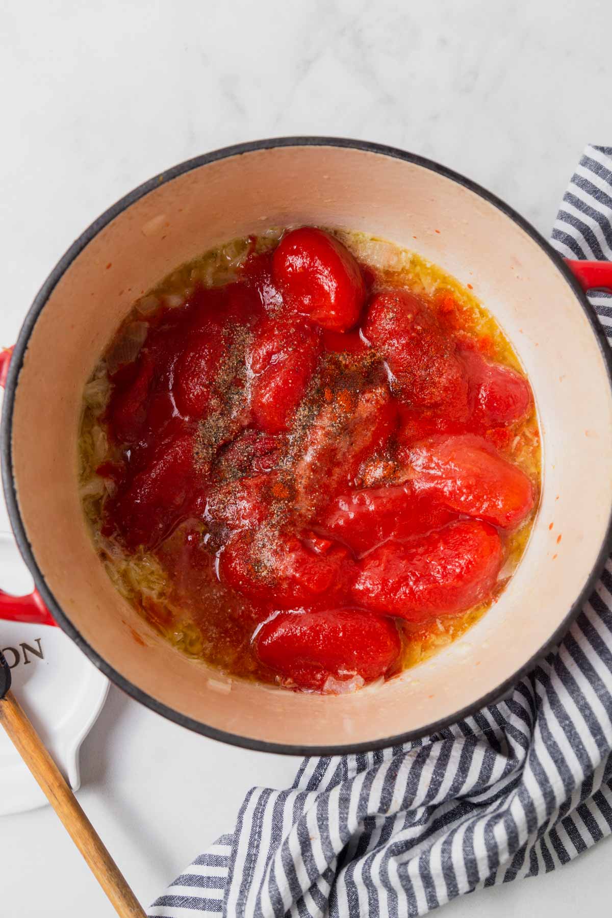 adding canned tomatoes and other ingredients to the pot.