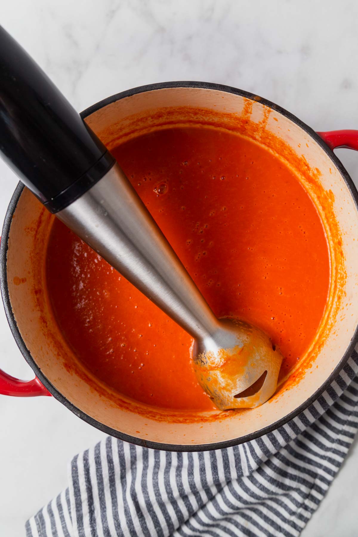 pureeing the tomato soup with a hand blender.