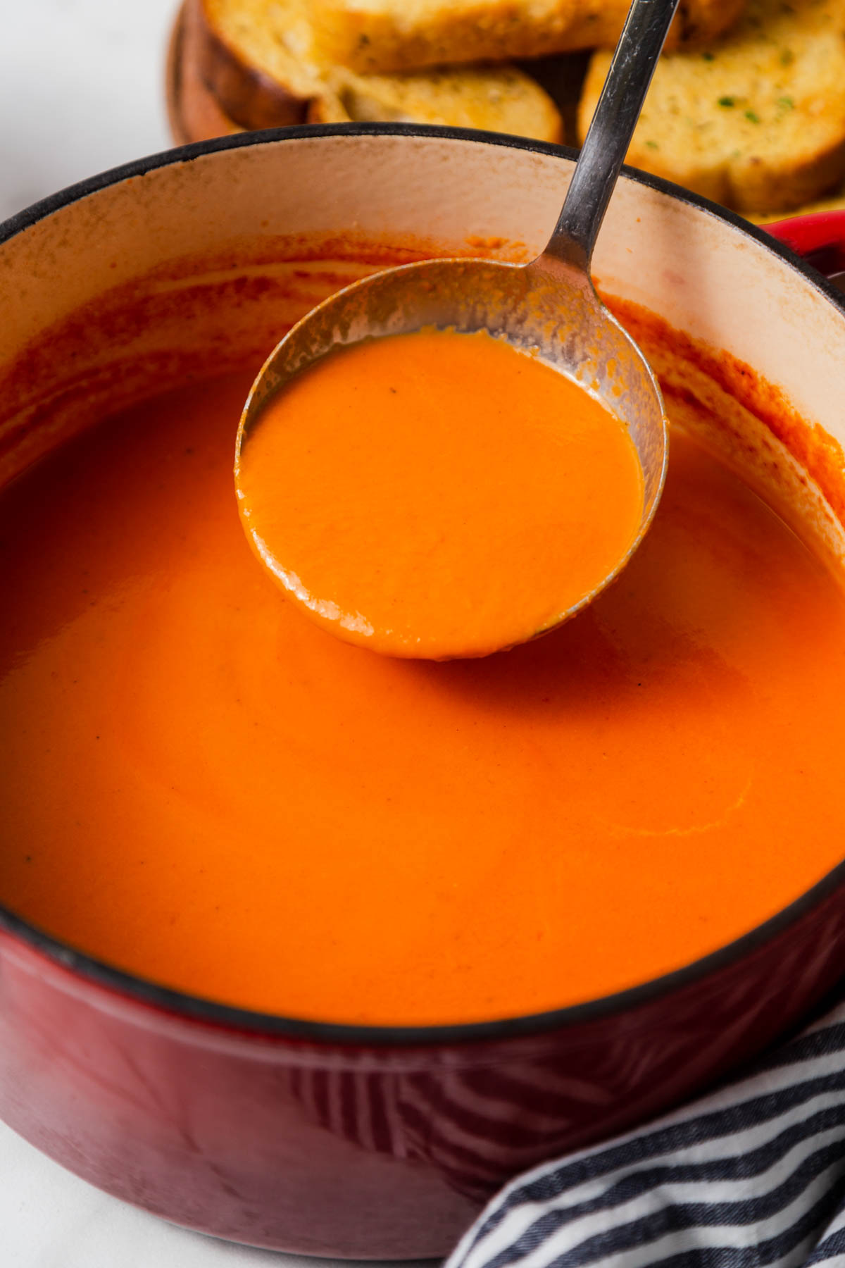 creamy tomato soup being ladled from the pot.