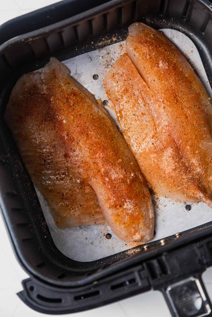 sprinkling the spices on the tilapia fillets.