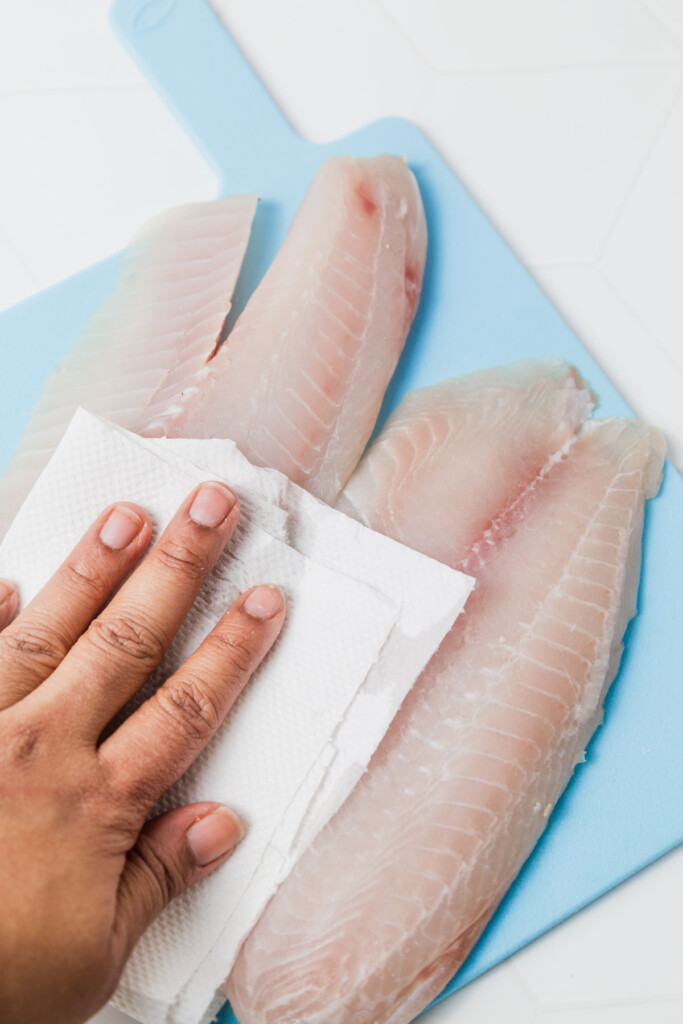 patting the tilapia fillets dry to remove excess moisture.