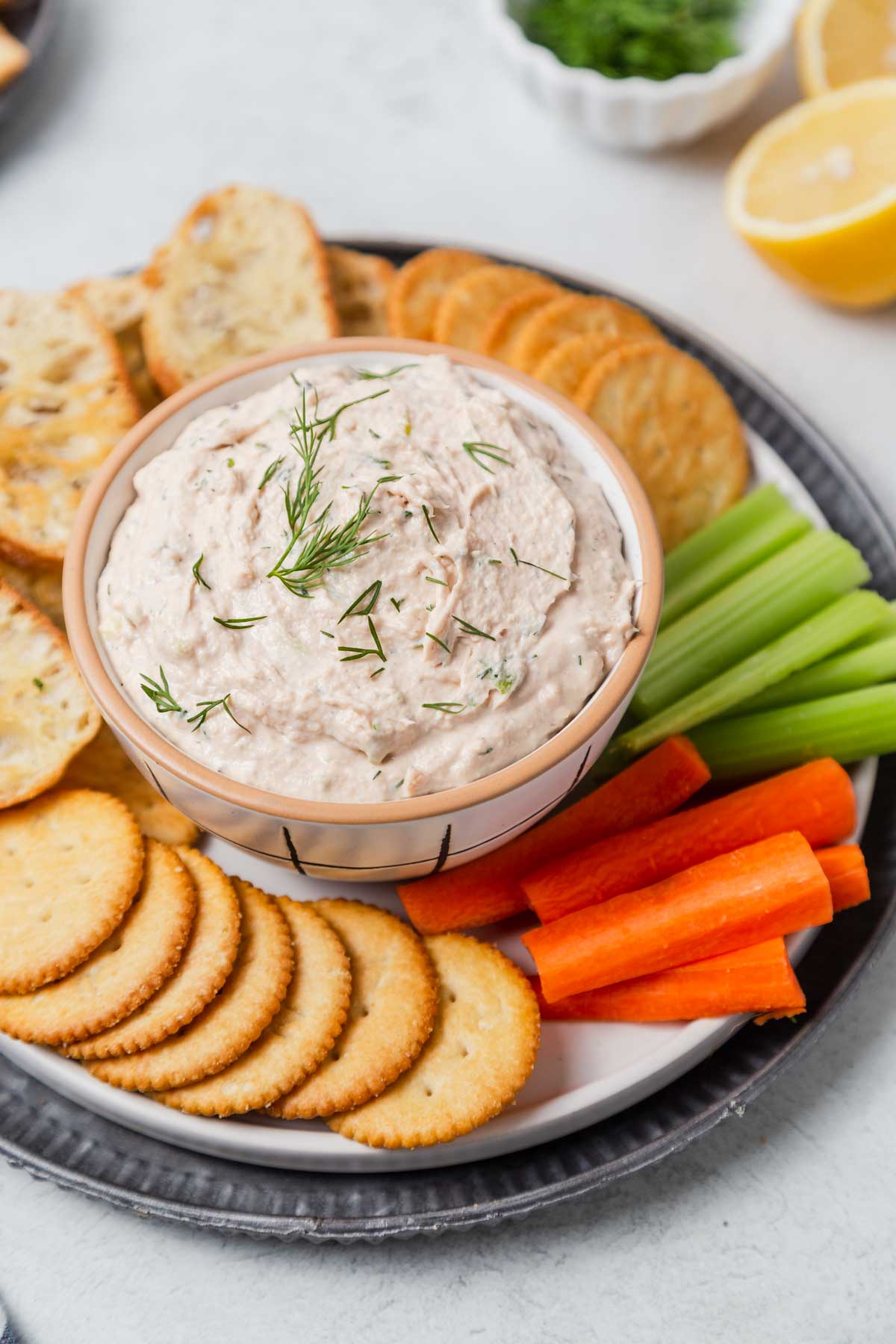 canned salmon dip with vegetables, crackers and crostini on a plate.