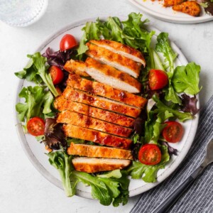 air fryer grilled chicken breasts with salad on a plate.