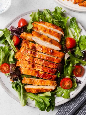 air fryer grilled chicken breasts with salad on a plate.