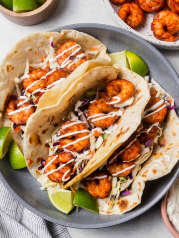 air fryer shrimp tacos on a plate with lime wedges.