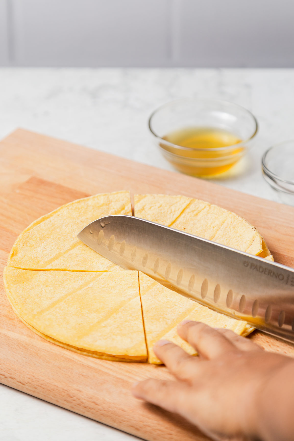 cutting tortillas on a cutting board with a sharp knife.