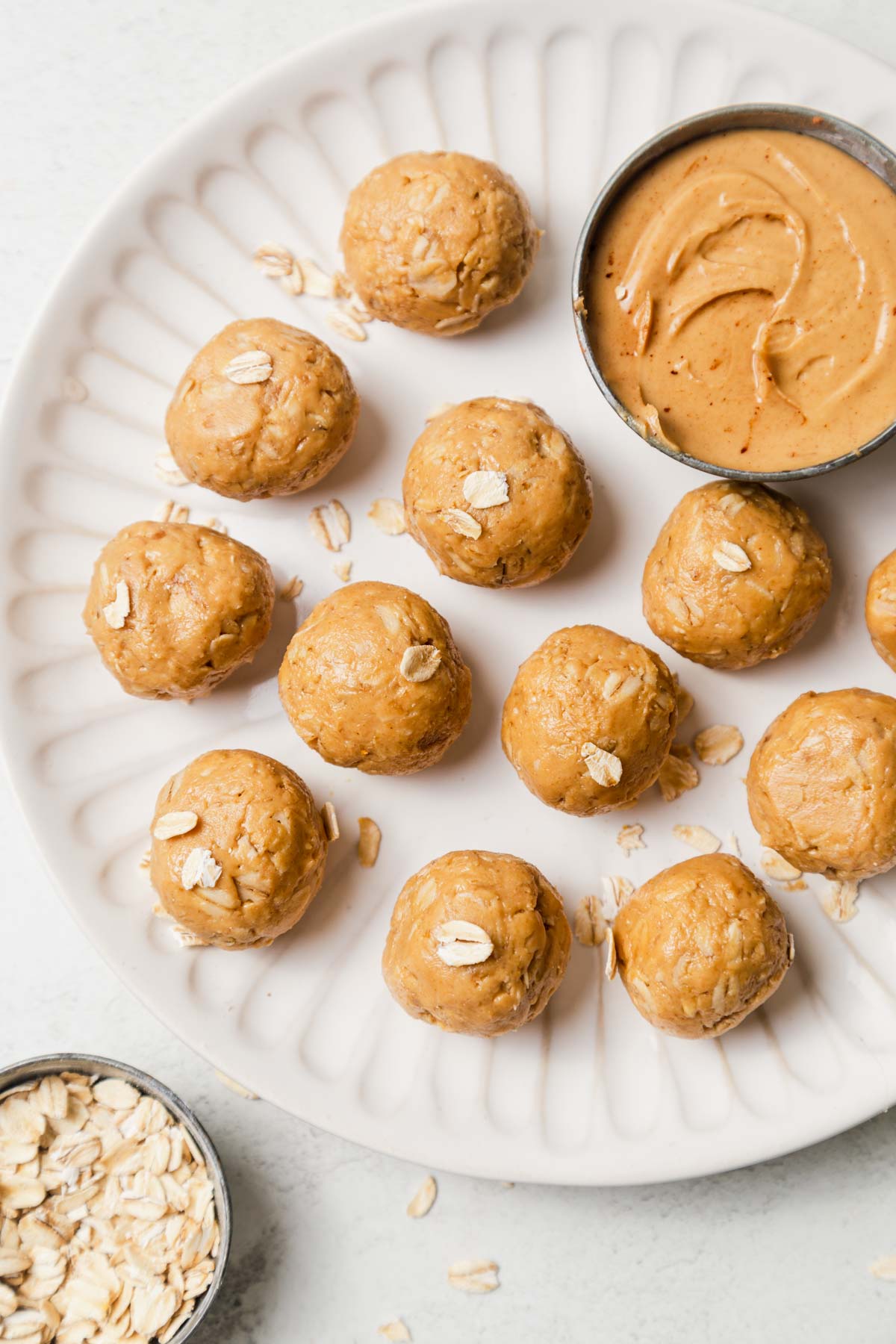 3 ingredient peanut butter balls on a plate with oats and peanut butter.
