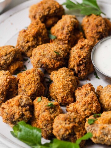 air fryer crispy breaded mushrooms on a plate with ranch dip.