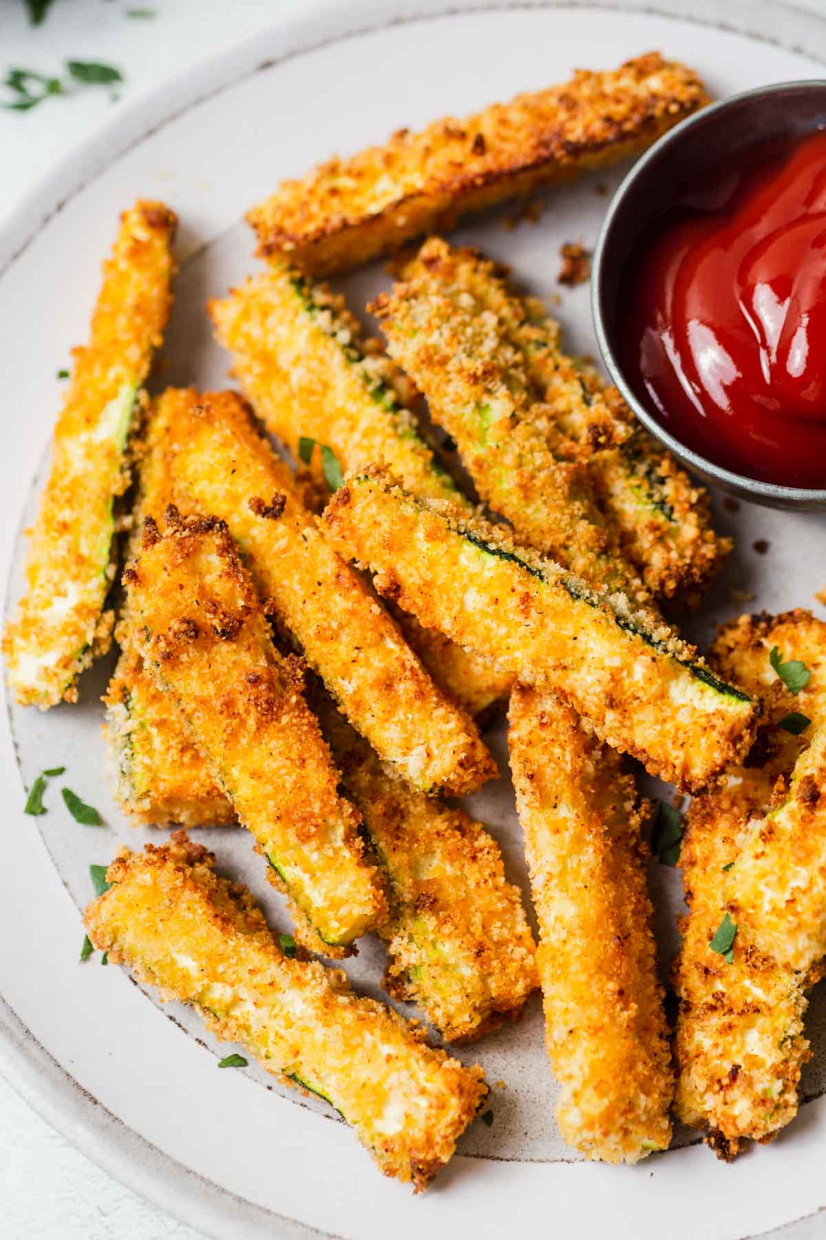 cripy air fryer zucchini fries on a plate with ketchup.
