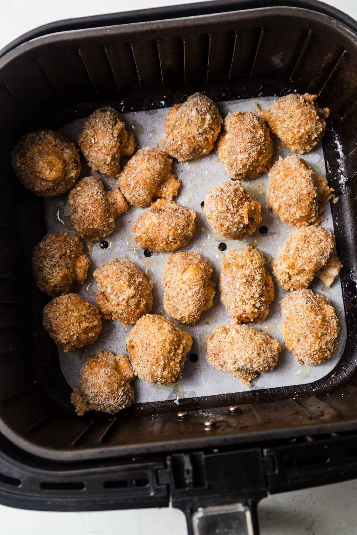 breaded mushrooms in the air fryer ready to be air fried.