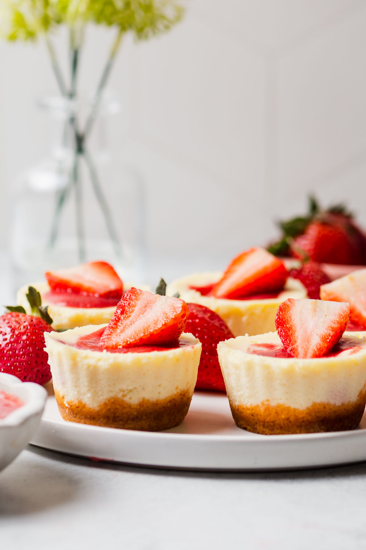 mini strawberry cheesecakes arranged on a platter against a white backdrop.
