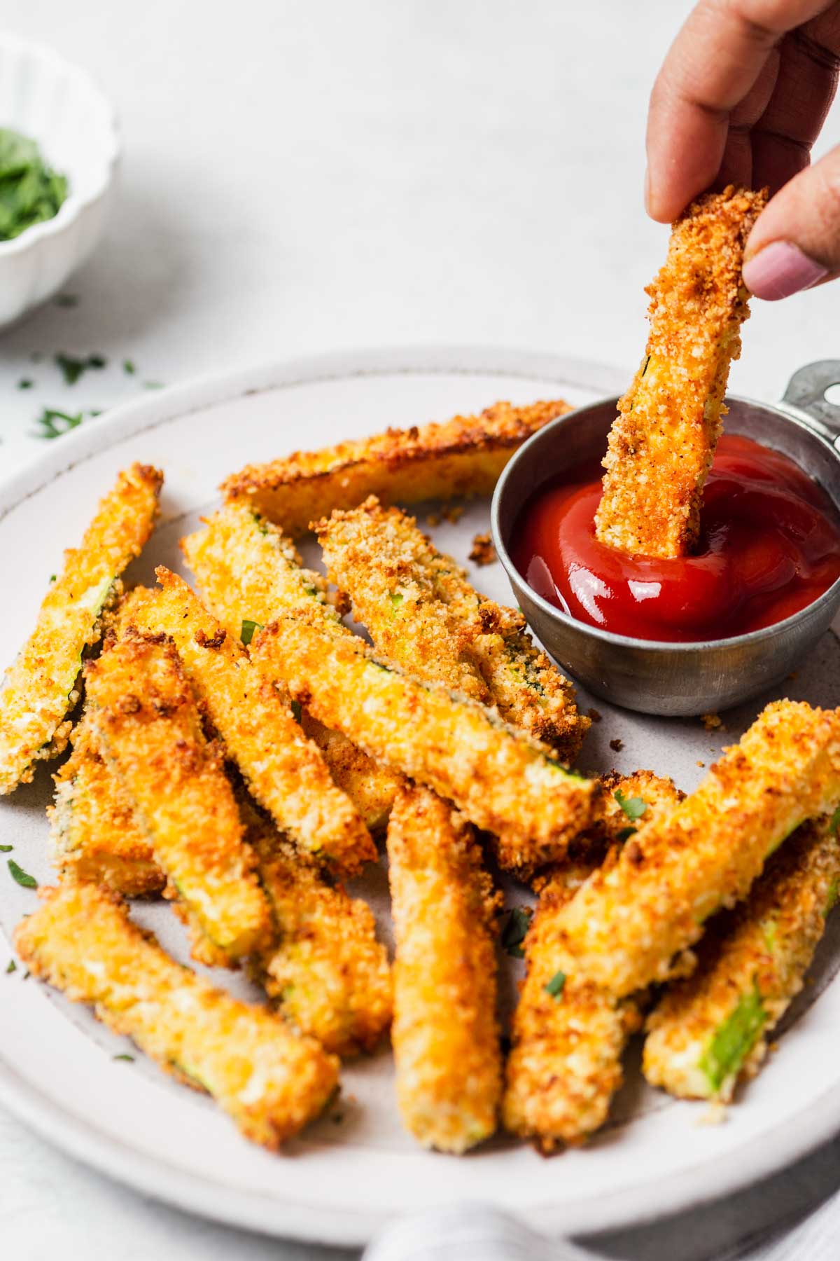 extra crispy parmesan air fried zucchini being dipped in ketchup.