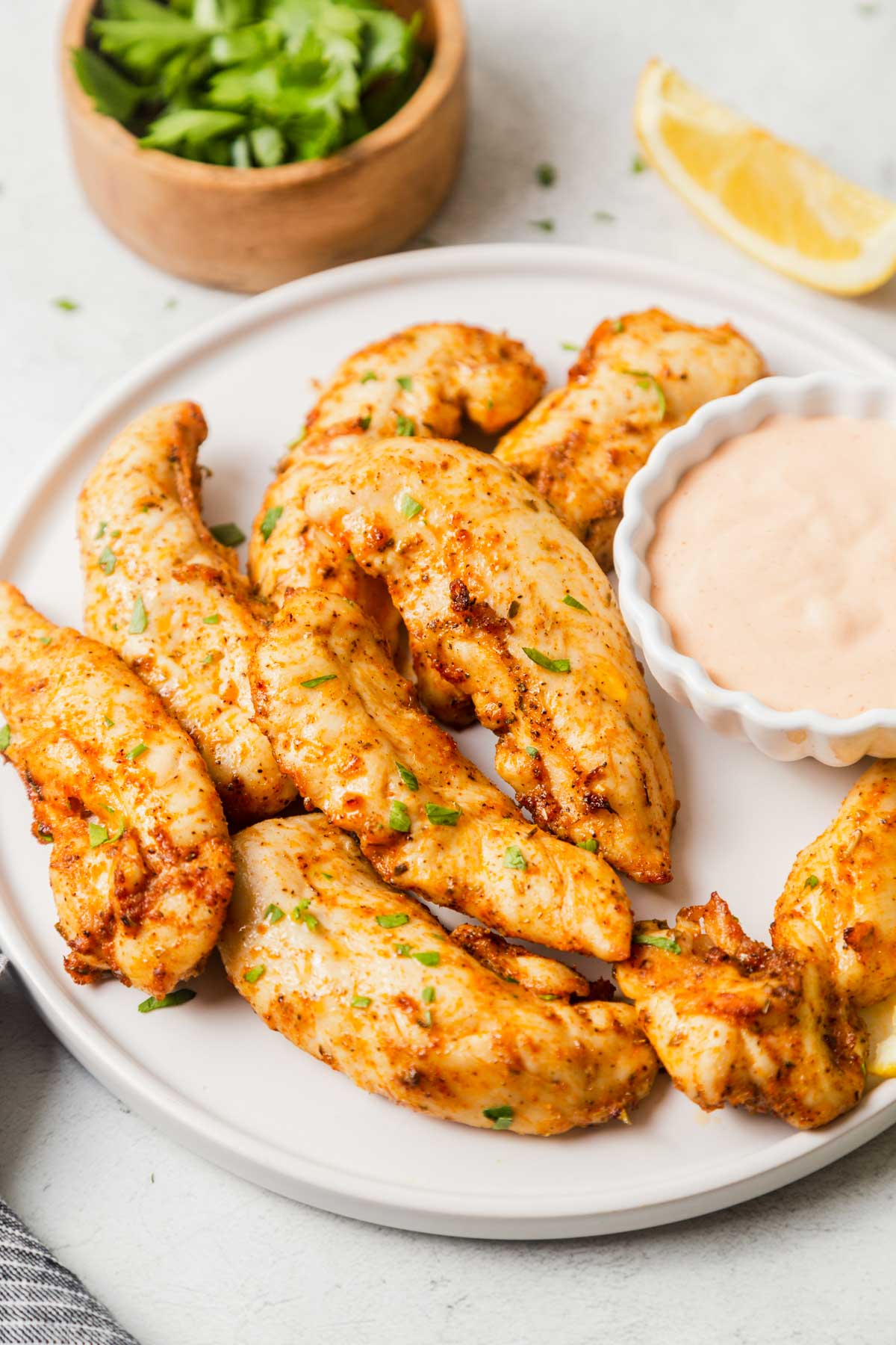 chicken tenders cooked in air fryer with dipping sauce on a plate.