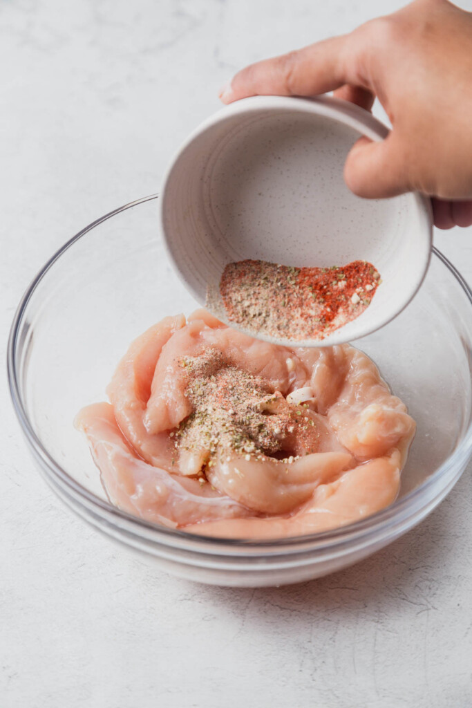 adding the spice mix to the chicken tenders.
